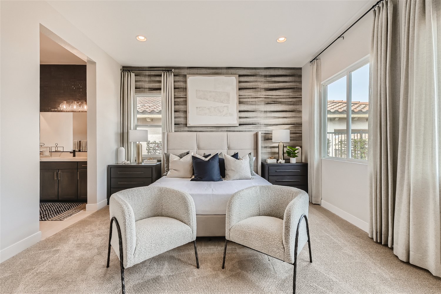 A bedroom with a bed and chairs.