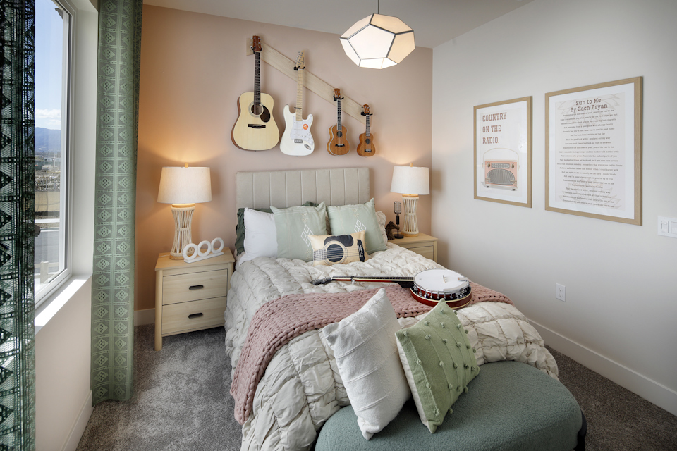 A bedroom with a bed and a guitar on the wall.