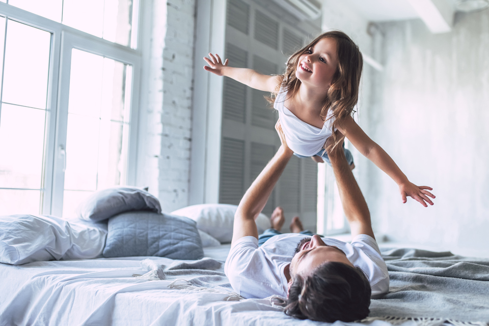 A woman standing on a man's back on a bed.
