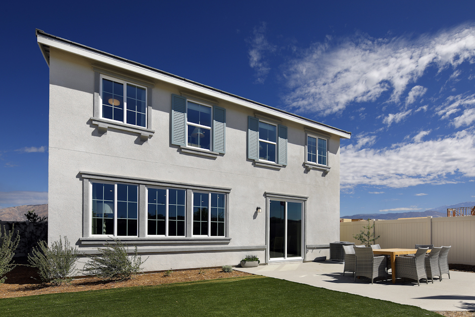 A white house with a lawn and chairs in front of it.