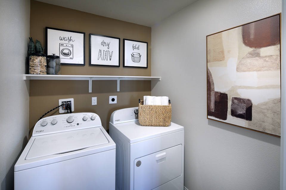 A white laundry room with a shelf and a basket on the wall.