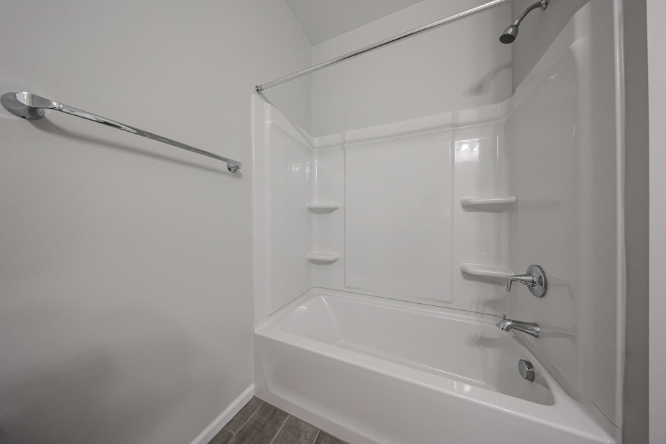 A bathroom with a bathtub and shower unit.