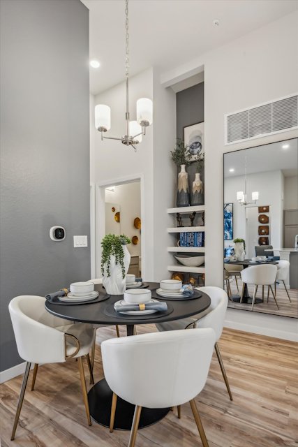 A dining room with a chandelier and a table with plates and cups on it.