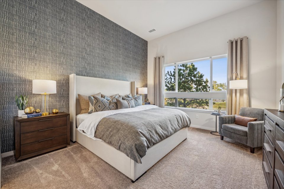A bedroom with a bed and a chair.