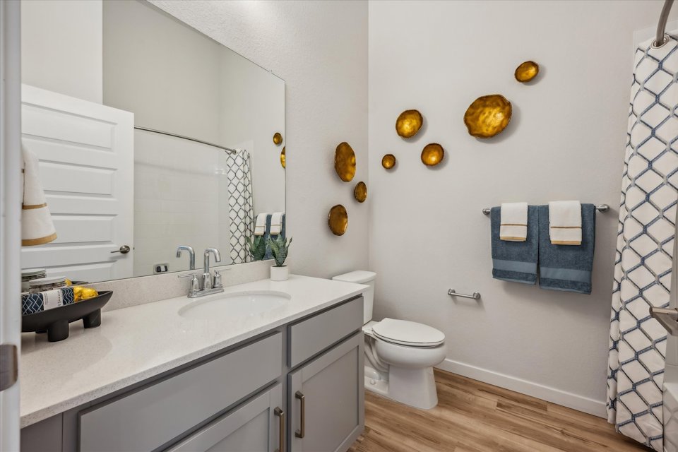 A bathroom with a sink toilet and mirror.