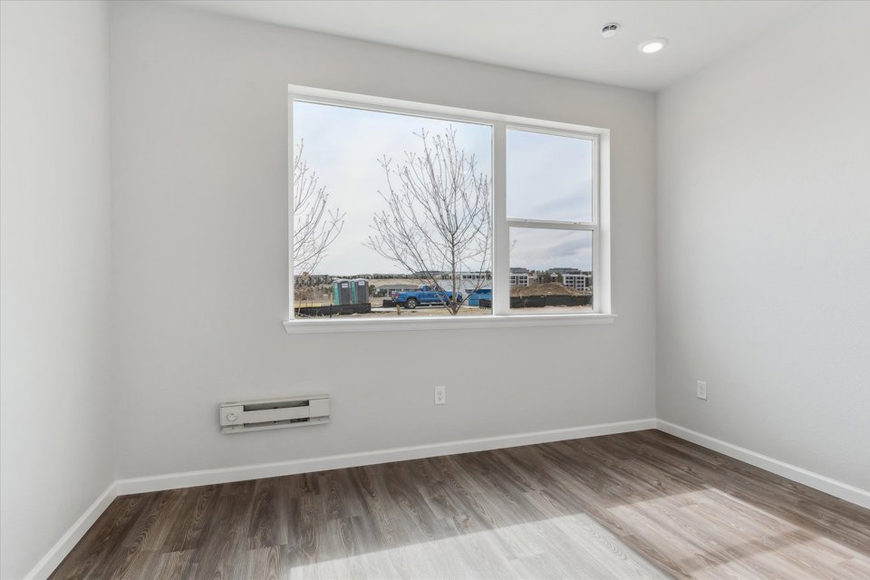 A room with a window and a wood floor.