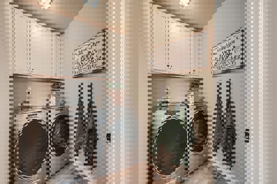 A laundry room with white cabinets.