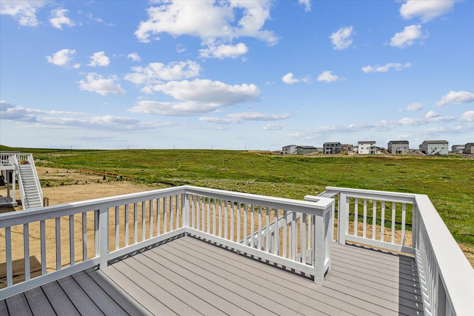 A deck overlooking a grassy field.