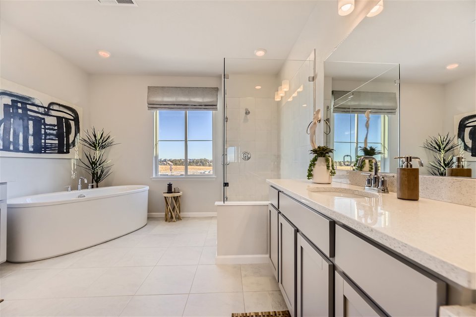 A bathroom with a tub sink and a large mirror.