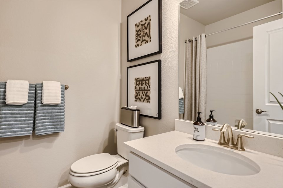 A bathroom with a sink toilet and mirror.