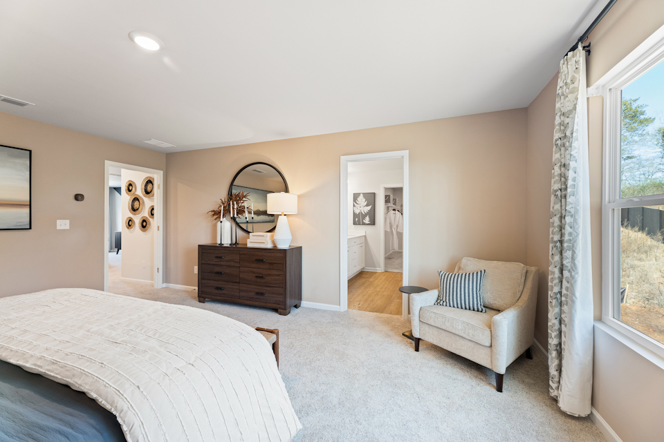 A bedroom with a bed and a chair.