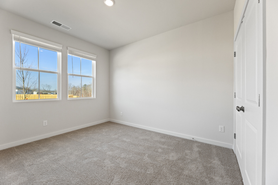 A room with a carpet and windows.