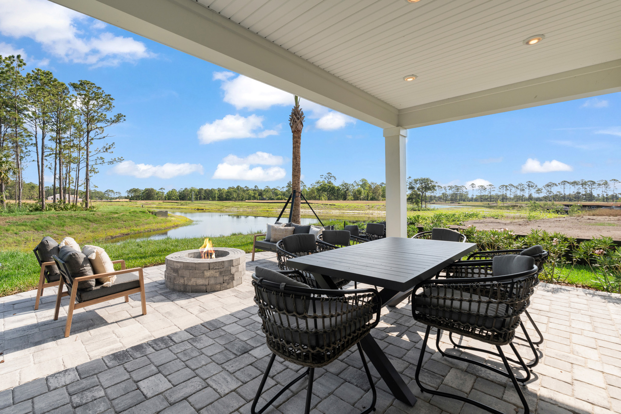 Kenai Model Home Covered Patio with Table and Chairs and Firepit at Reserve East in Flagler Beach