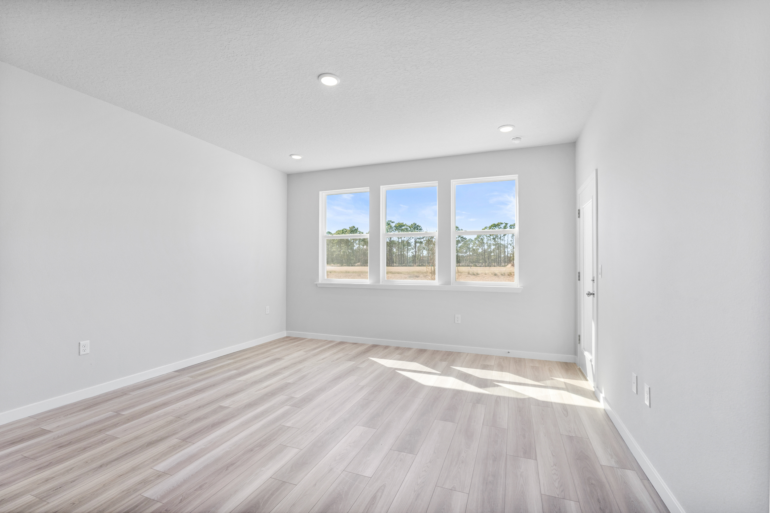 Lot 197 Primary Bedroom with LVP Floors and Door to Patio at Reserve East