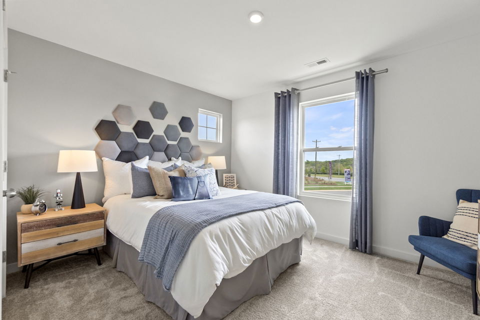 A bedroom with a bed and a chair.