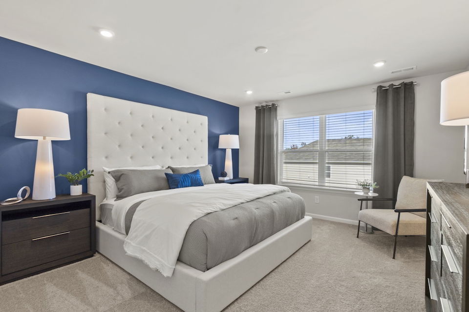 A bedroom with a bed and chairs.