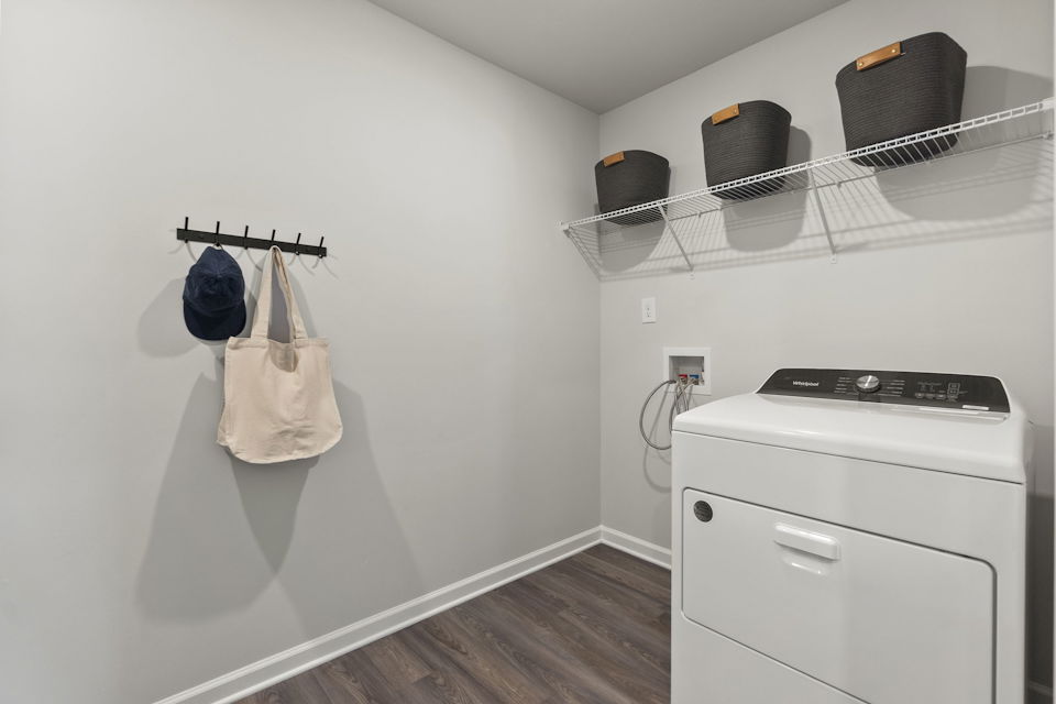 A white room with a white wall and a white stove with a white towel on the wall.