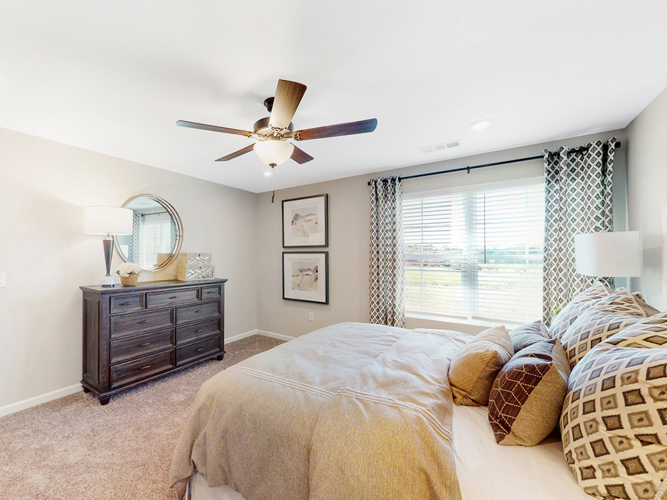 A bedroom with a fan and bed.