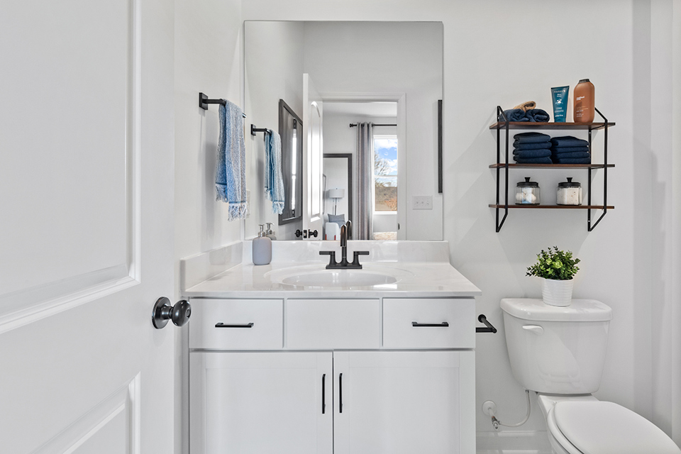 A bathroom with a sink toilet and mirror.