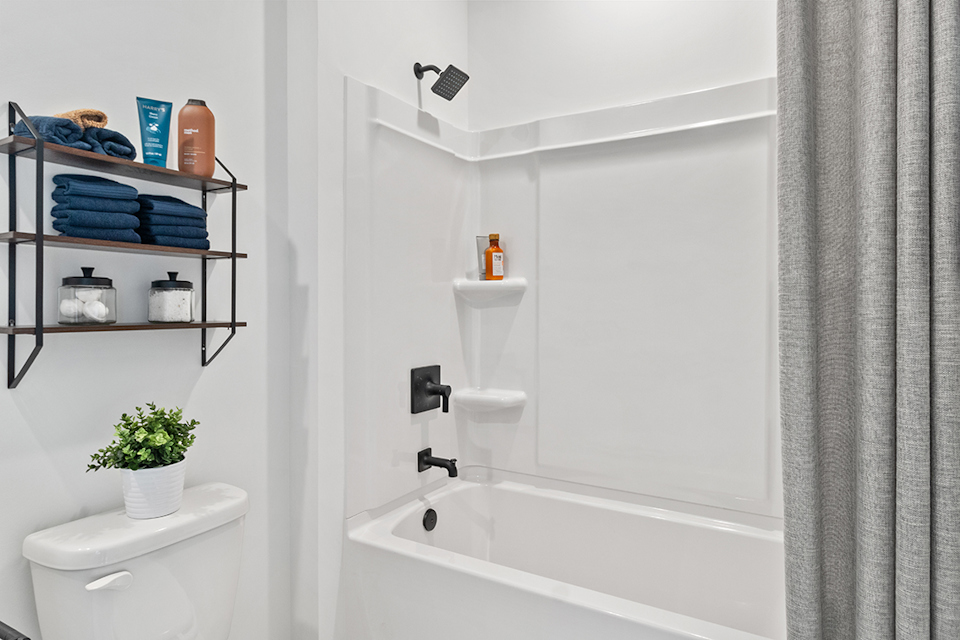 A bathroom with a tub toilet and shelves.