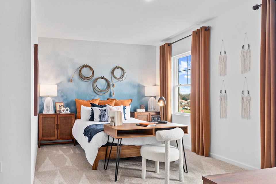 A bedroom with a bed desk and a mirror.