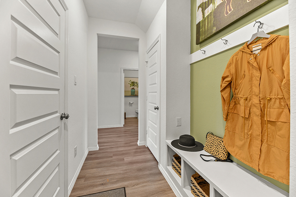 A room with a hat and a coat rack.