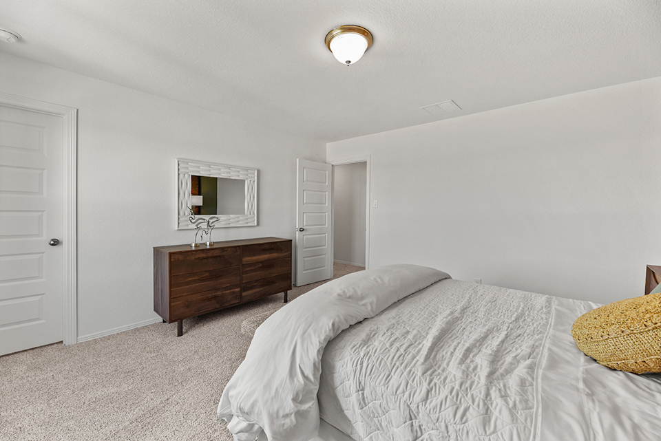 A bedroom with a bed and a dresser.