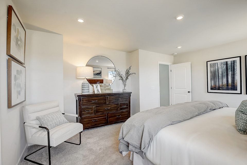 A bedroom with a bed and a chair.