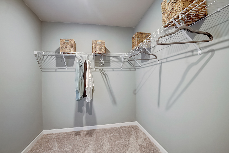 A white wall with a white shelf and a basket with clothes.