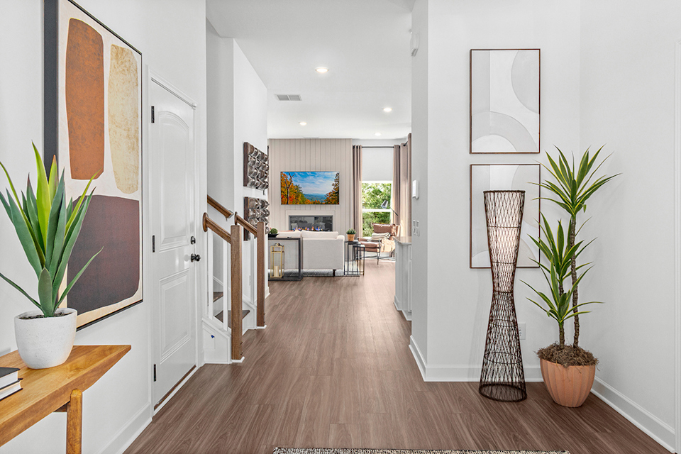 A room with a wood floor and a wood floor with a vase and a plant in it.