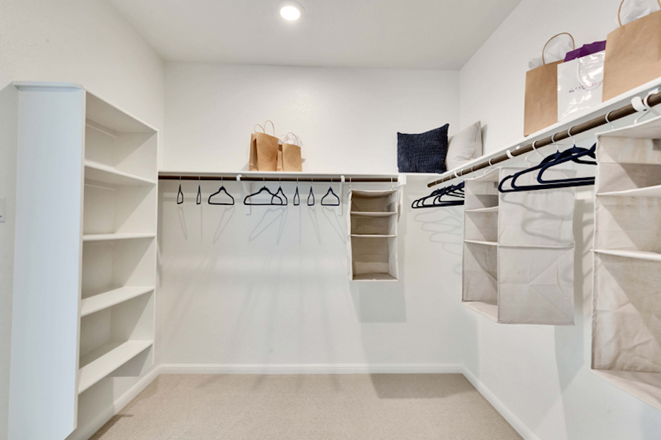 A white closet with white shelves.