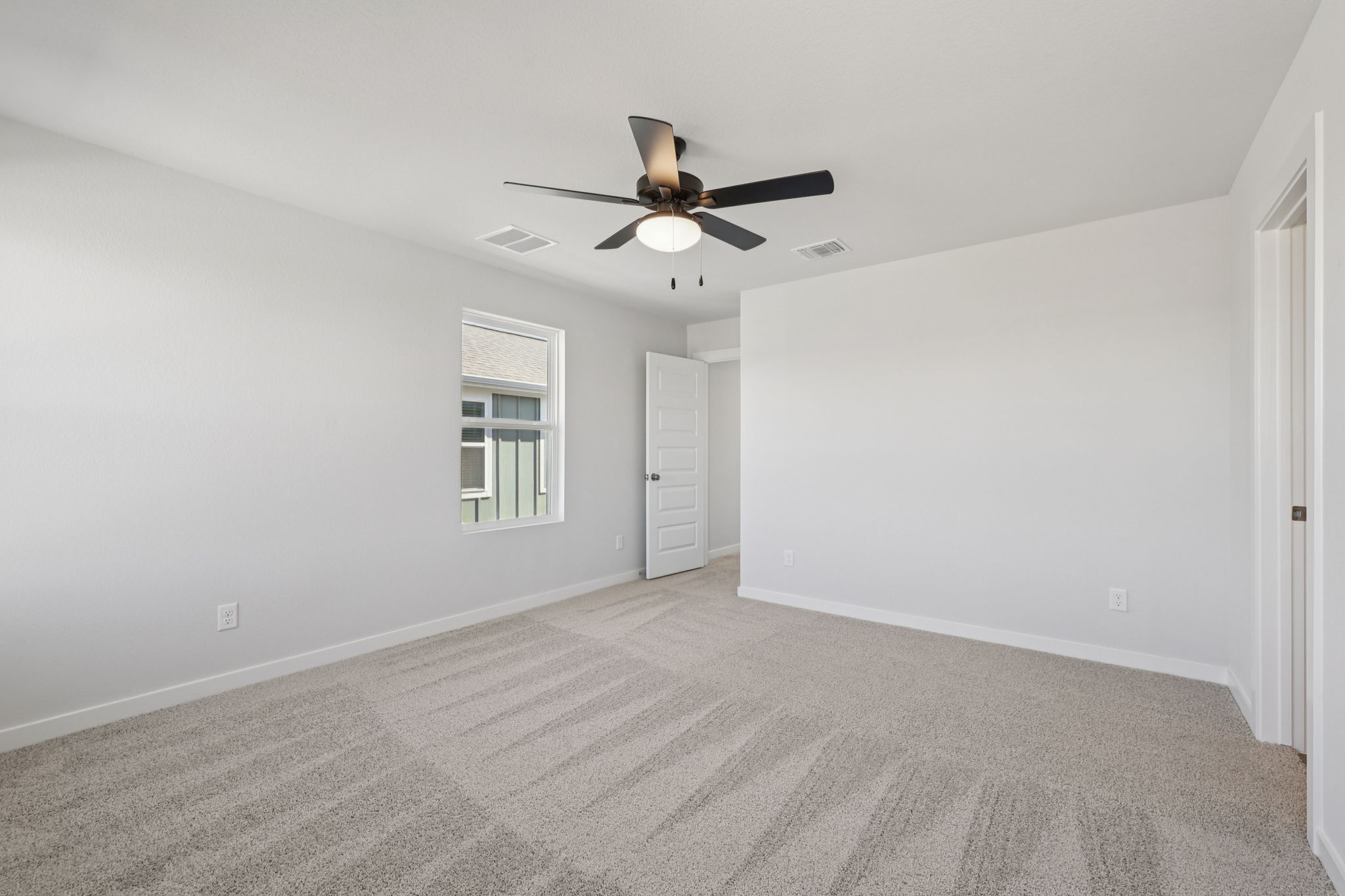 A room with a ceiling fan and a carpet.
