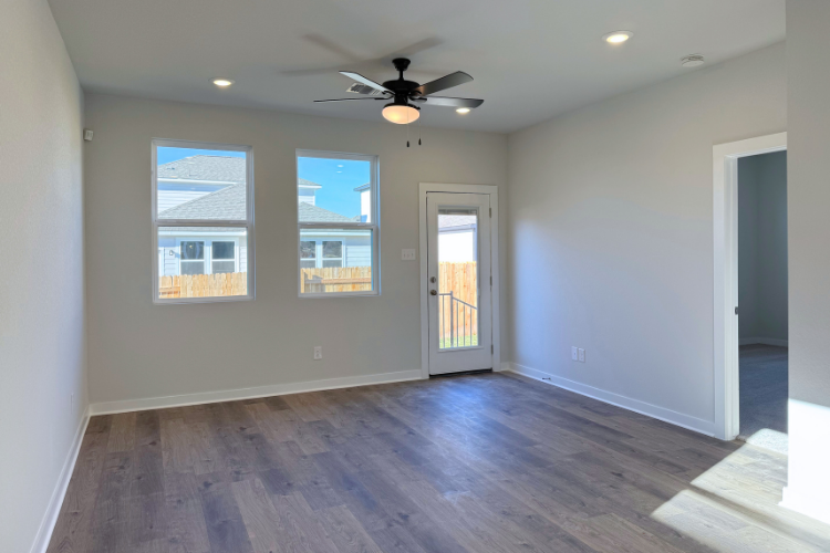 A room with a wood floor and a ceiling fan and a wood floor.