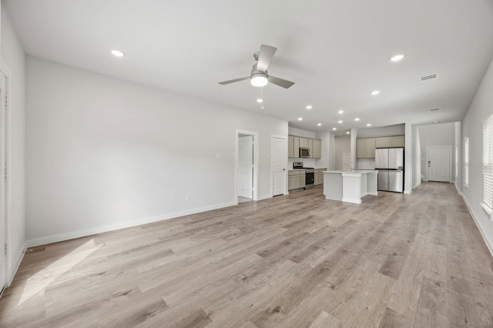 A large empty room with a wood floor and a ceiling fan.