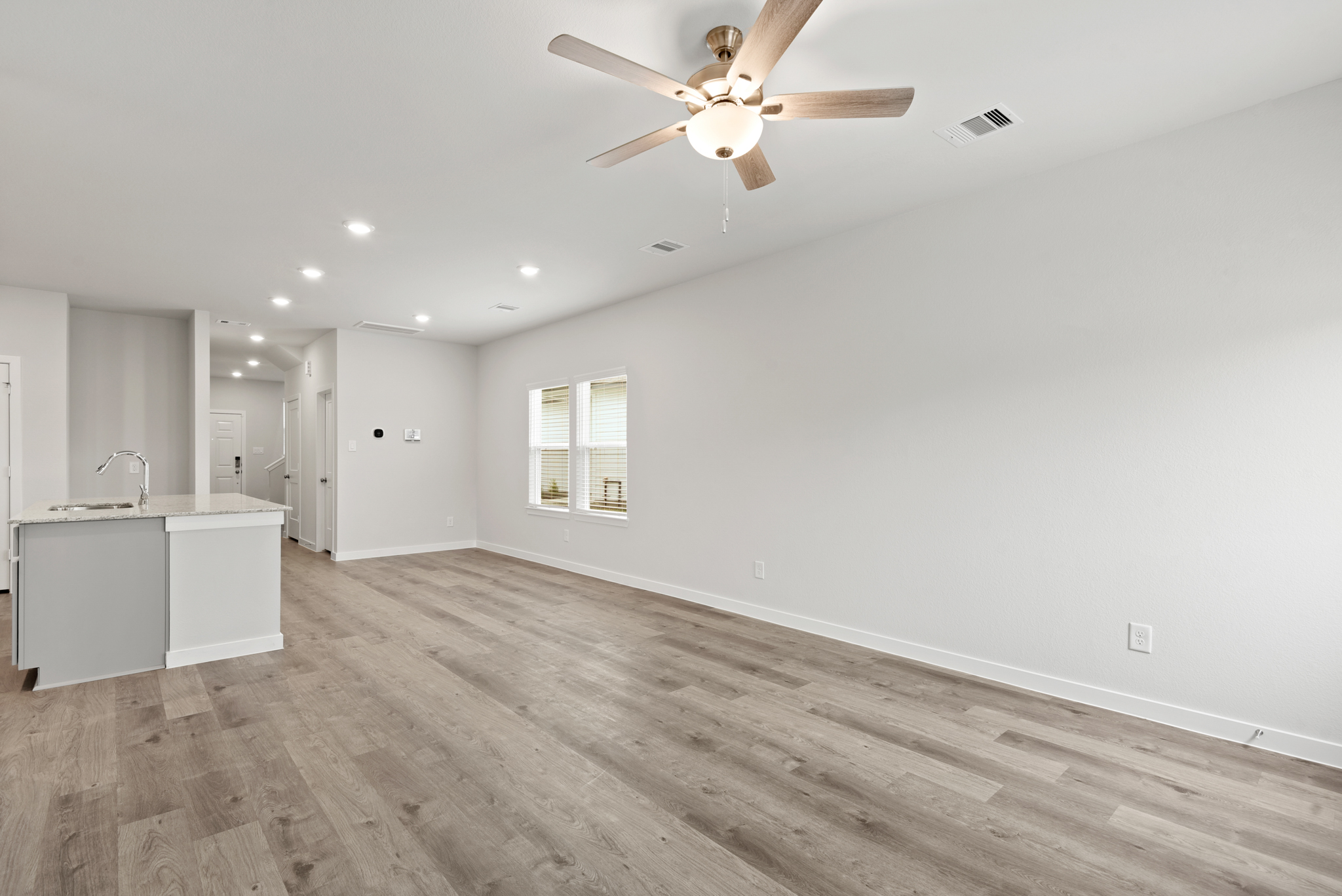 A room with a ceiling fan and cabinets.
