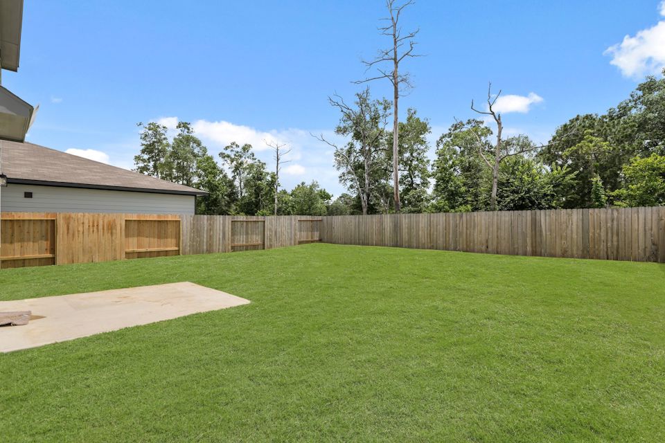 A fenced in yard with a wood fence and trees in the background.