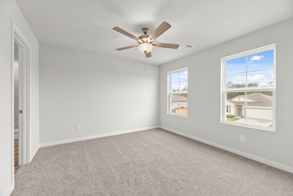 A room with a ceiling fan and windows.