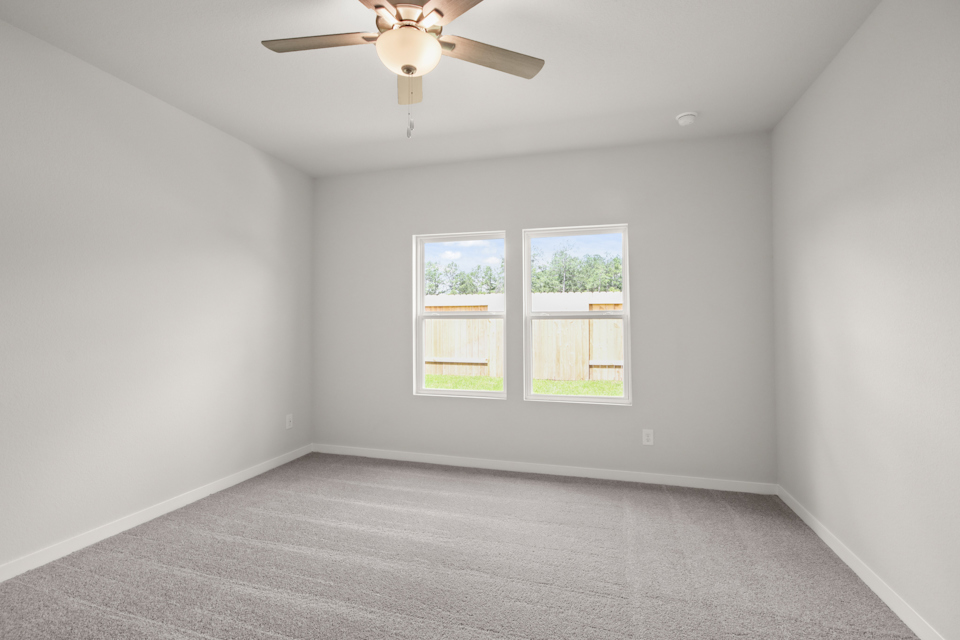 A room with a ceiling fan and windows.