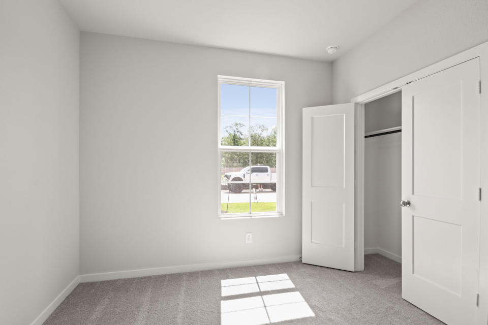 A room with white walls and a window with a car outside.