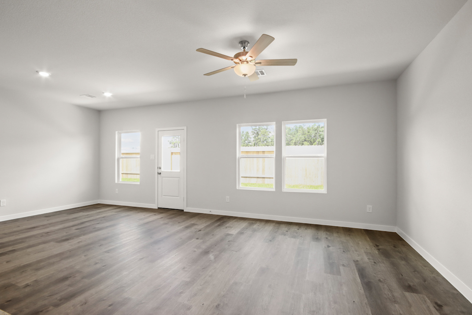 A room with a ceiling fan and a wood floor.