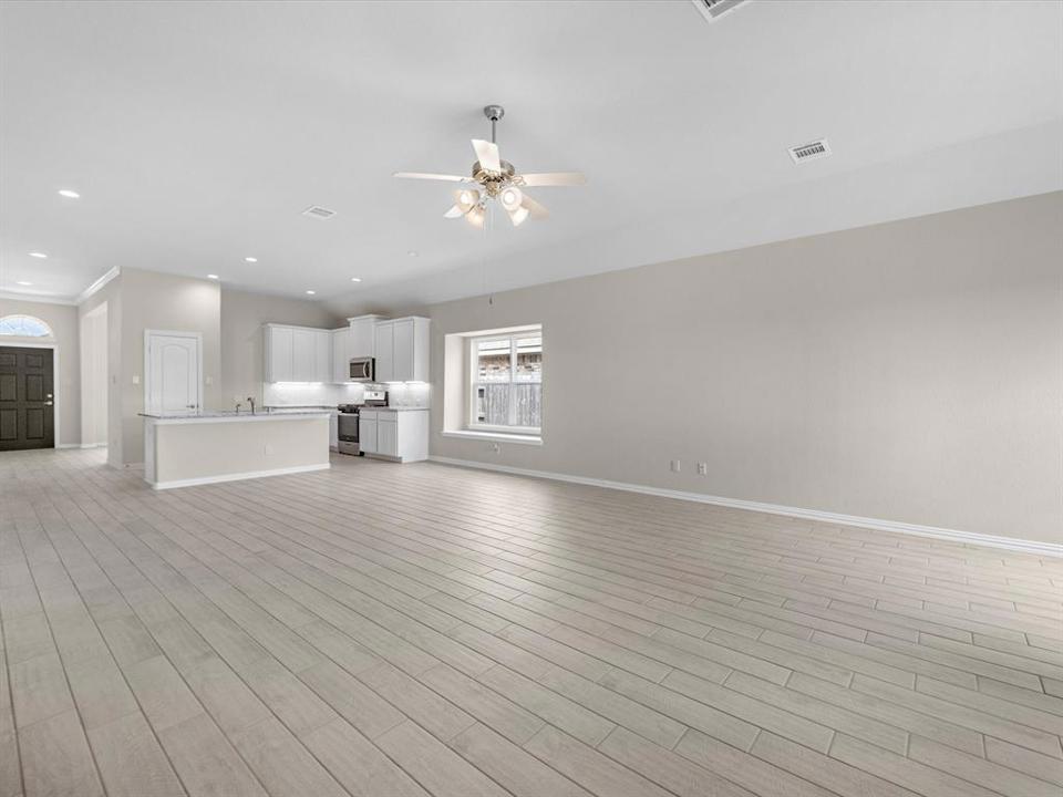 A large empty room with a wood floor and a ceiling fan.