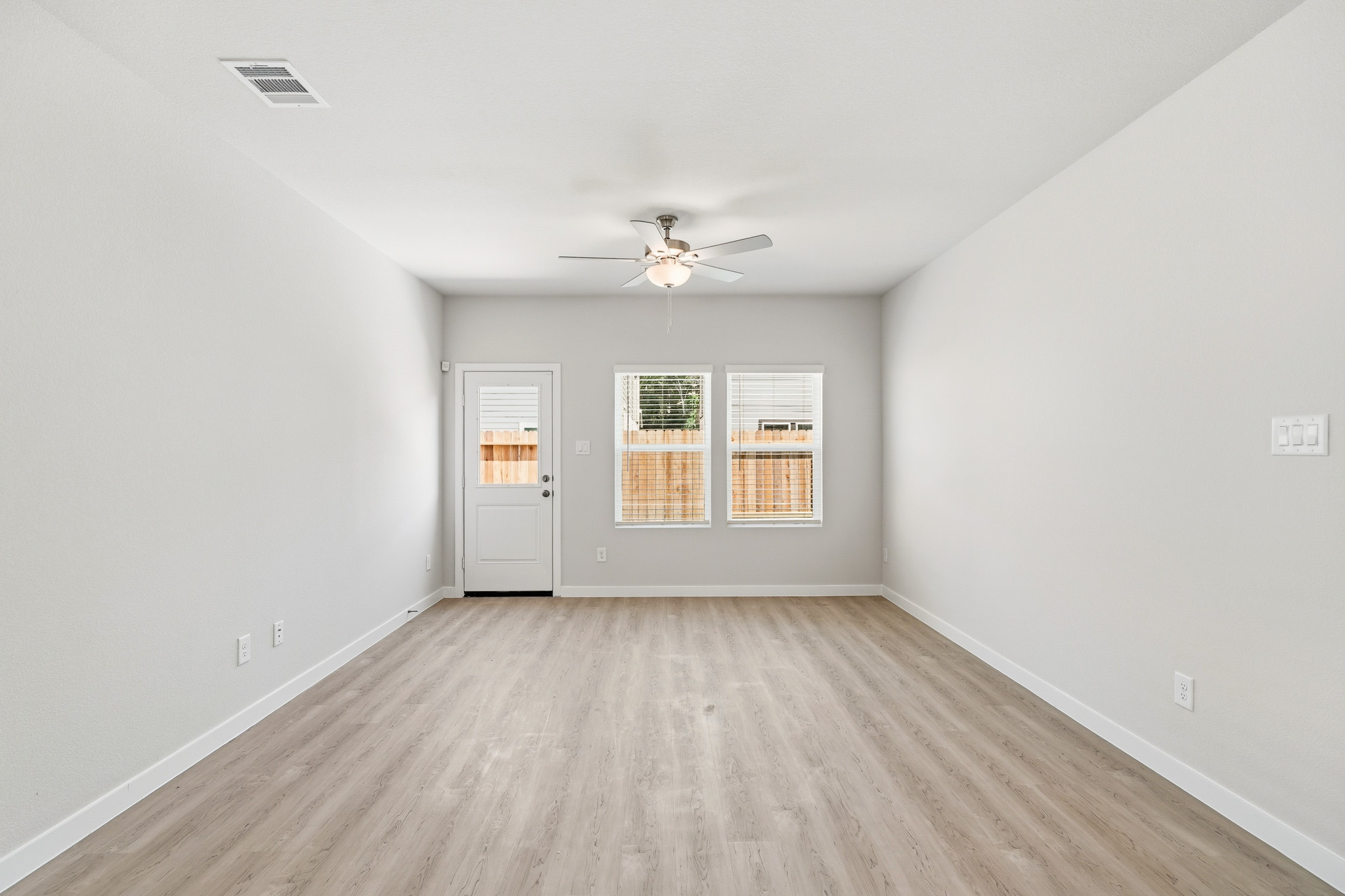 A room with a wood floor and a ceiling fan.