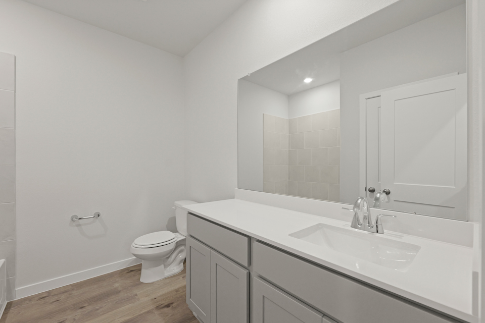 A bathroom with a sink toilet and mirror.
