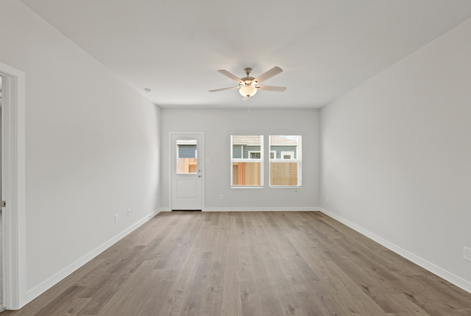 A room with a ceiling fan and a wood floor.