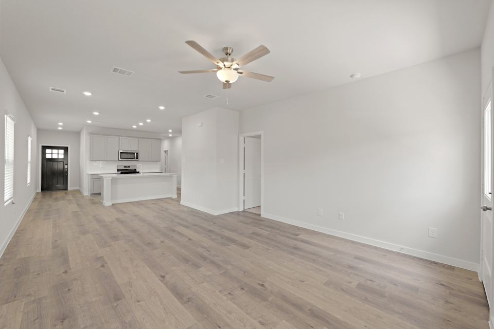 A large empty room with a wood floor and a ceiling fan.