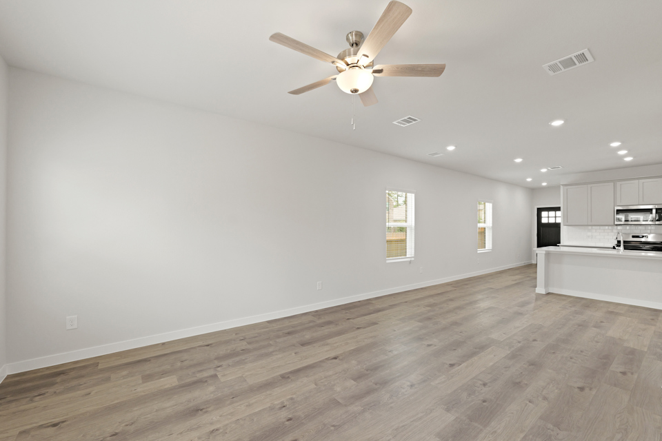 A large room with a ceiling fan and a wood floor.