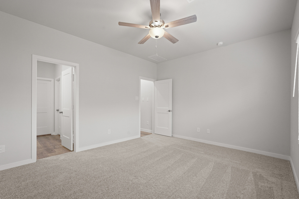 A room with a ceiling fan and white doors.