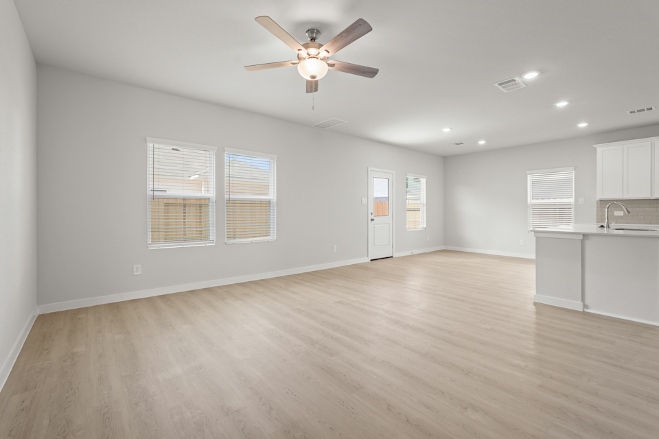 A large empty room with a ceiling fan and a wood floor.
