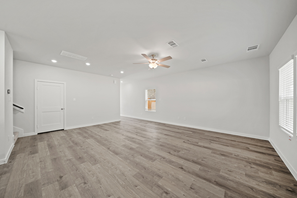 A room with a wood floor and a ceiling fan.