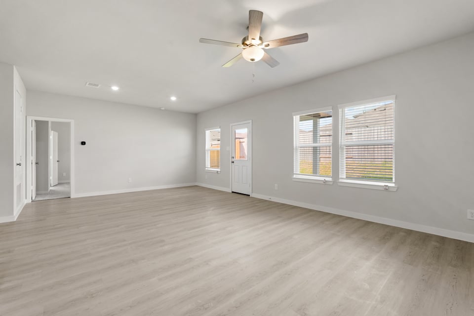 A room with a ceiling fan and a wood floor.